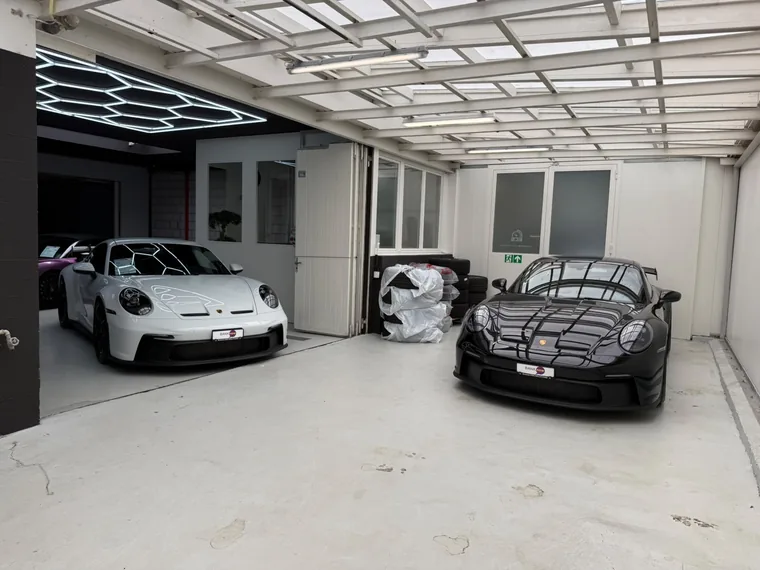 Zwei Porsche 911 GT3 in Weiss und Schwarz vor dem Showroom